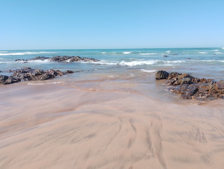 Gentle waves on a calm beach with rocky shoreline in soft light