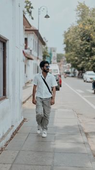 Casual man strolling down a sunny street in Thiruvananthapuram, India, showcasing urban life.