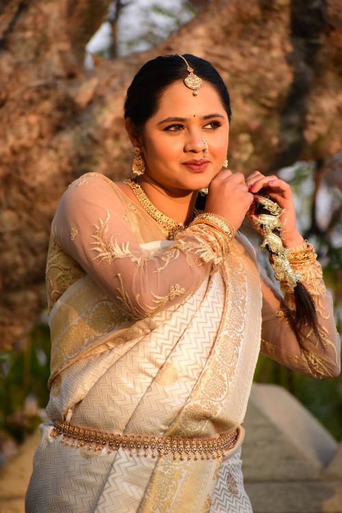 Free Woman dressed in traditional Indian saree adjusting jewelry outdoors. Stock Photo