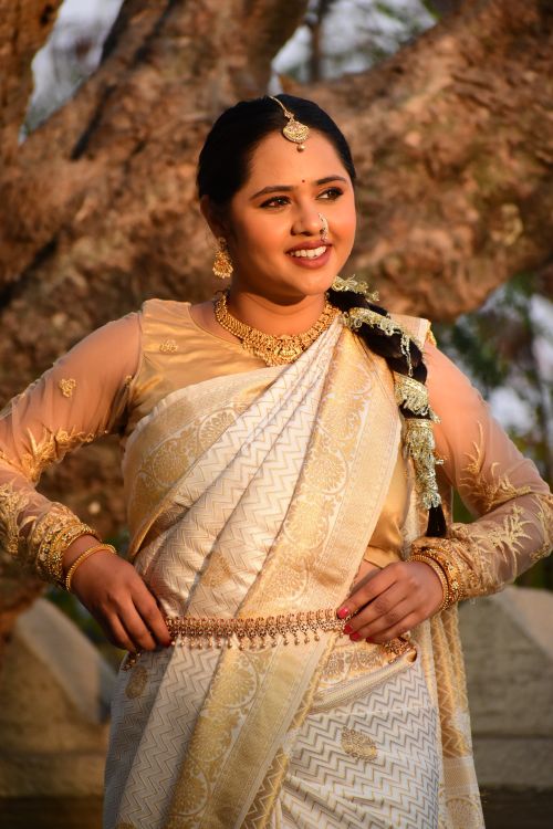 Free Woman in an intricate gold sari poses outdoors, exuding cultural elegance and joy. Stock Photo