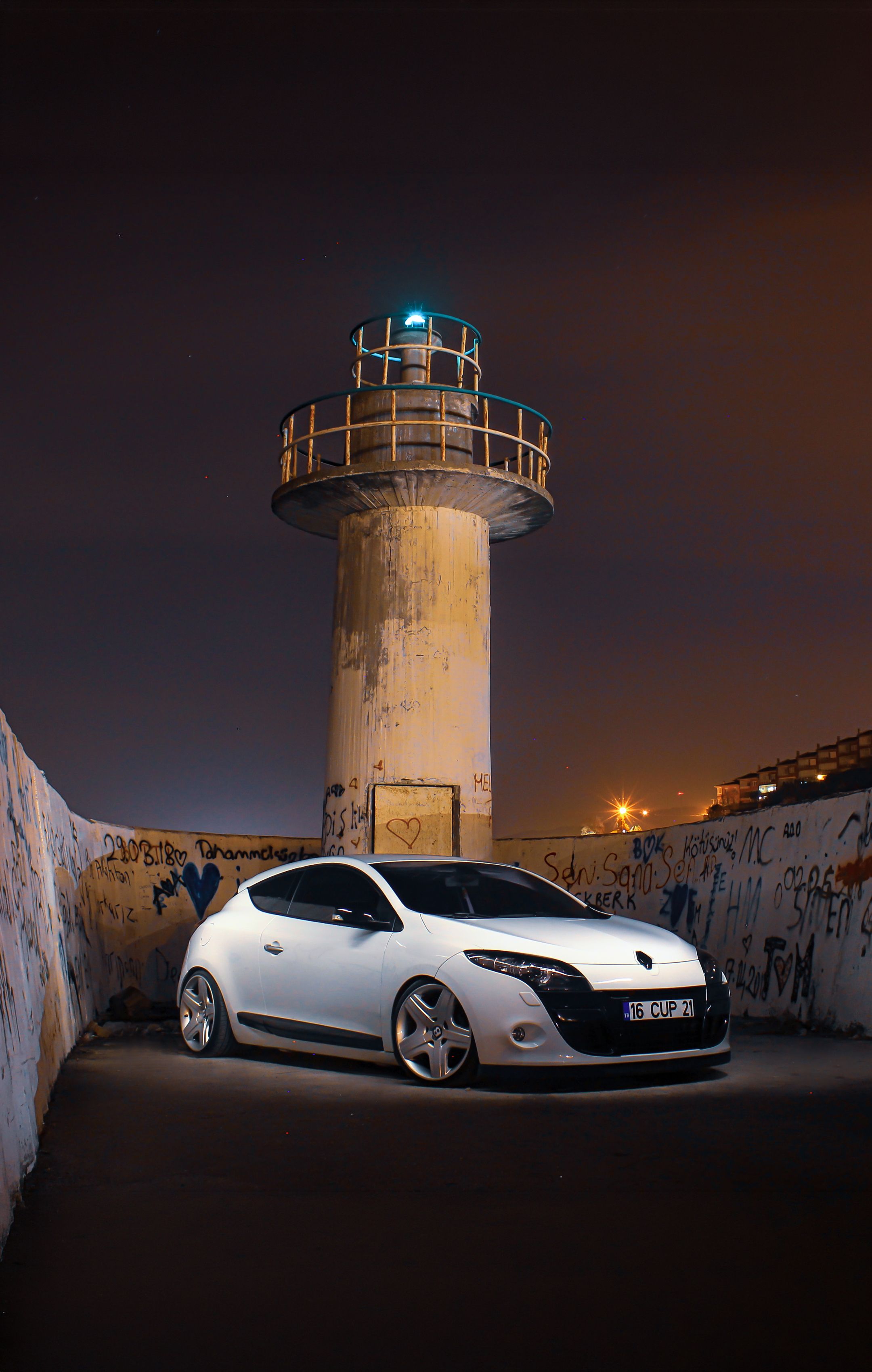 Sleek Car by Graffiti-Covered Lighthouse · Free Stock Photo