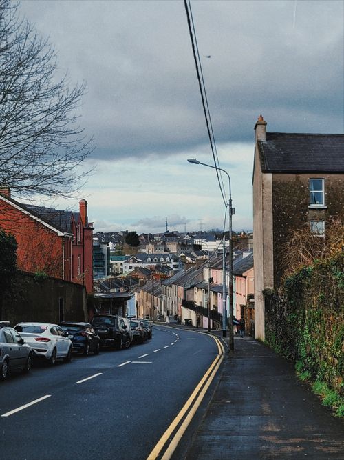Free A peaceful urban street view with colorful buildings and parked cars. Perfect for illustrating small-town charm. Stock Photo