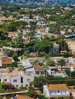Aerial view of a picturesque Mediterranean village with white villas and lush greenery, capturing summer vibes.