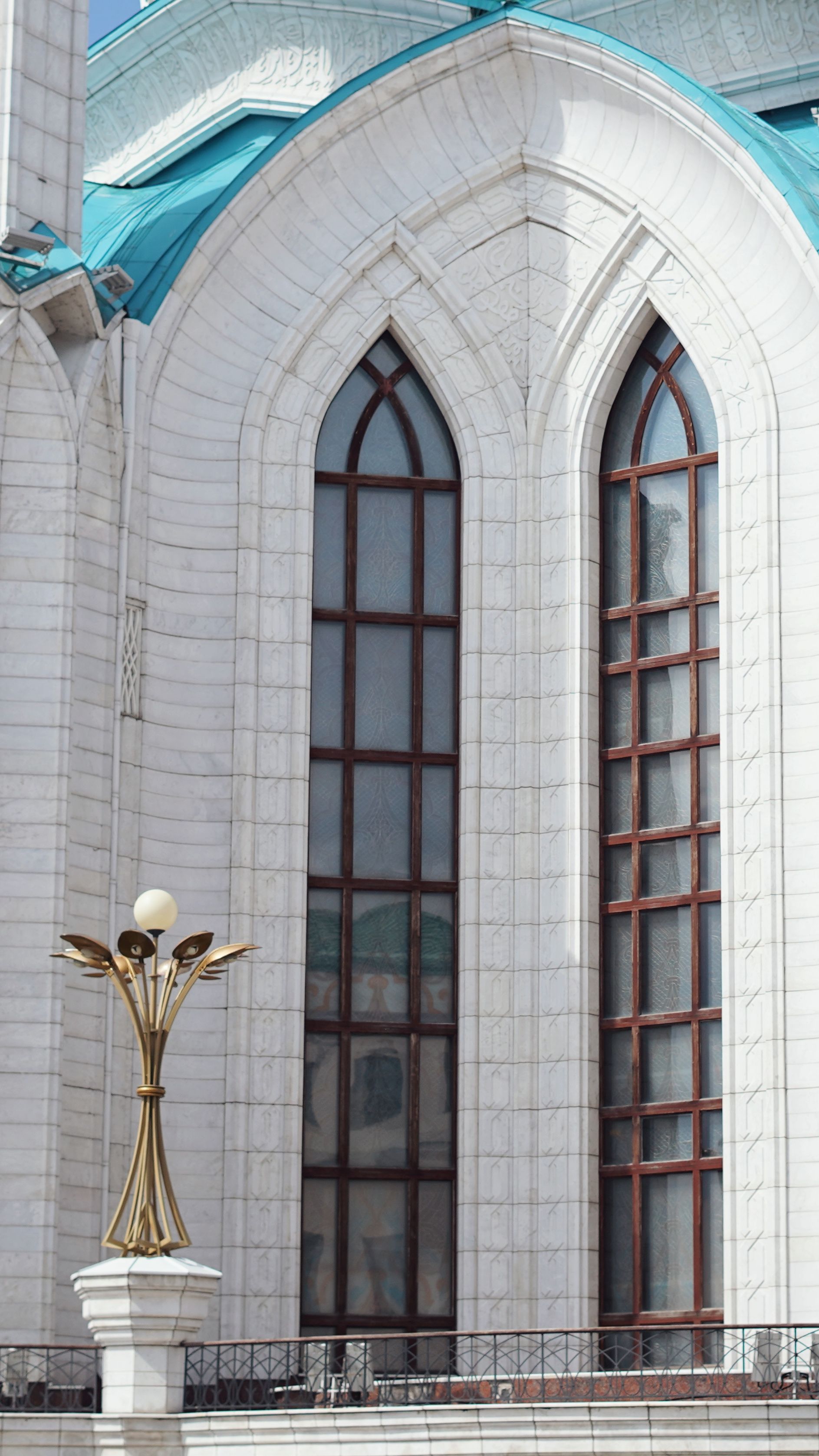 Elegant architectural detail of Kul Sharif Mosque in Kazan, Russia, featuring gothic-inspired windows and a golden lamppost.