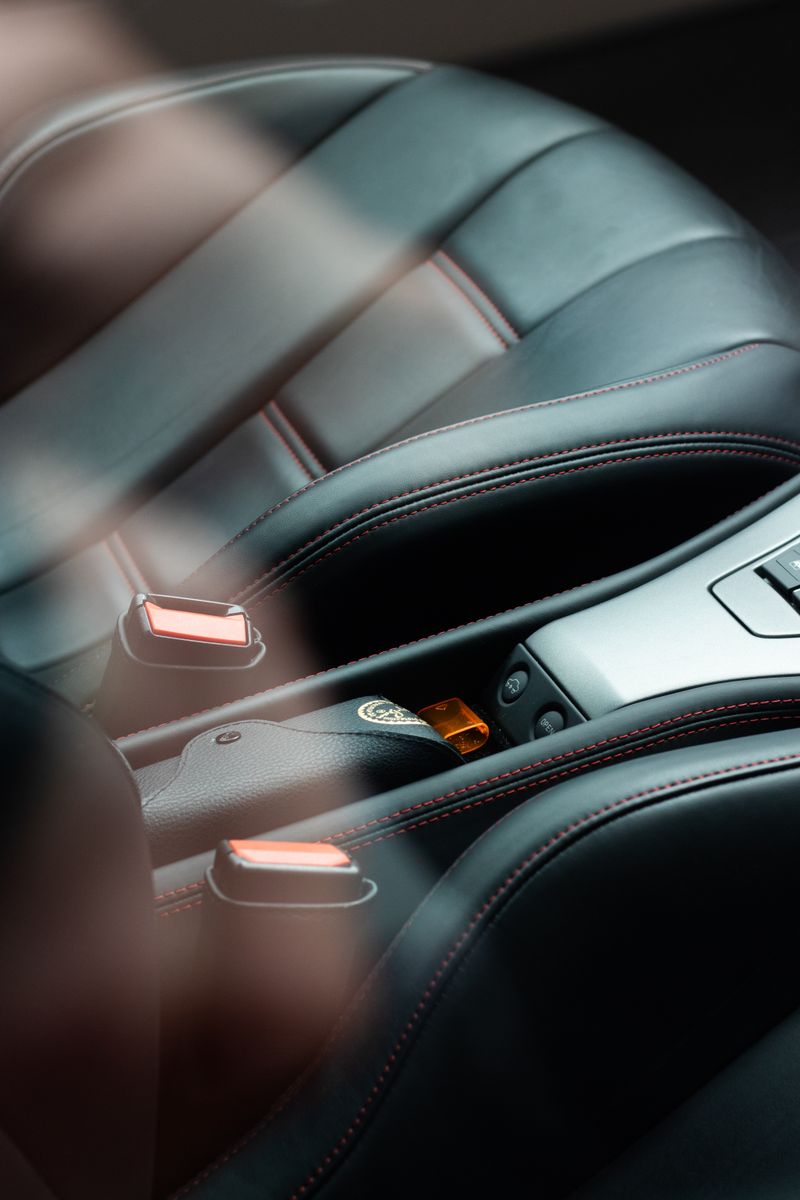 Detailed shot of black leather car seats with red stitching, showcasing modern automotive design.