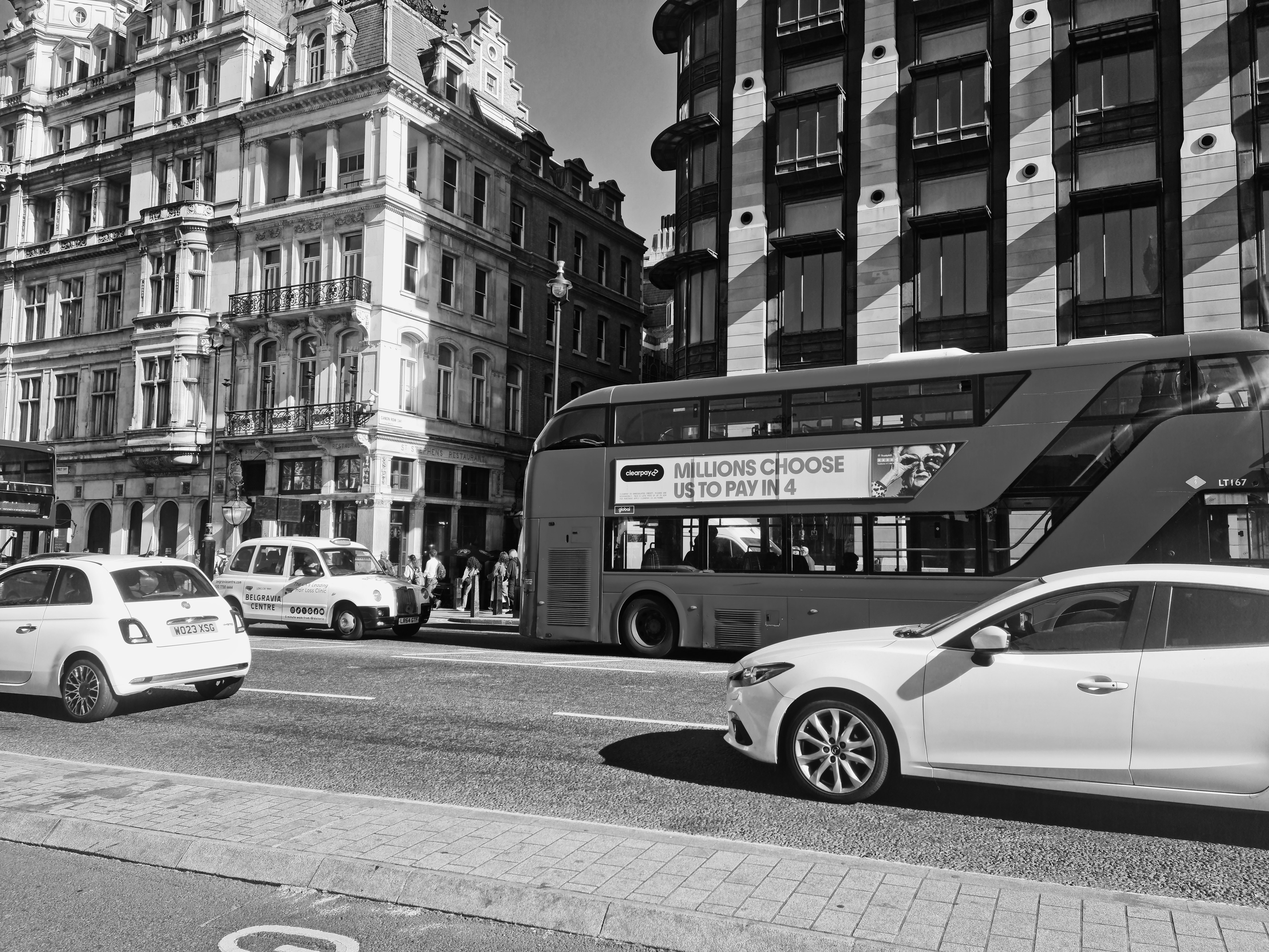 Classic London street view featuring iconic red double-decker bus and historic architecture in monochrome.