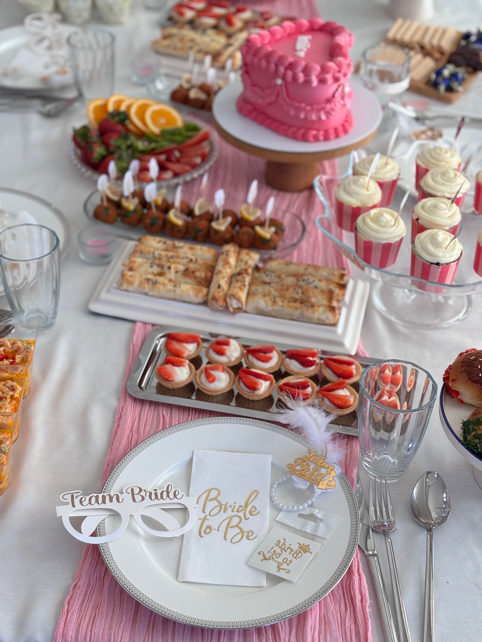A bridal-shower buffet with sweets, fruit, and serving pieces.