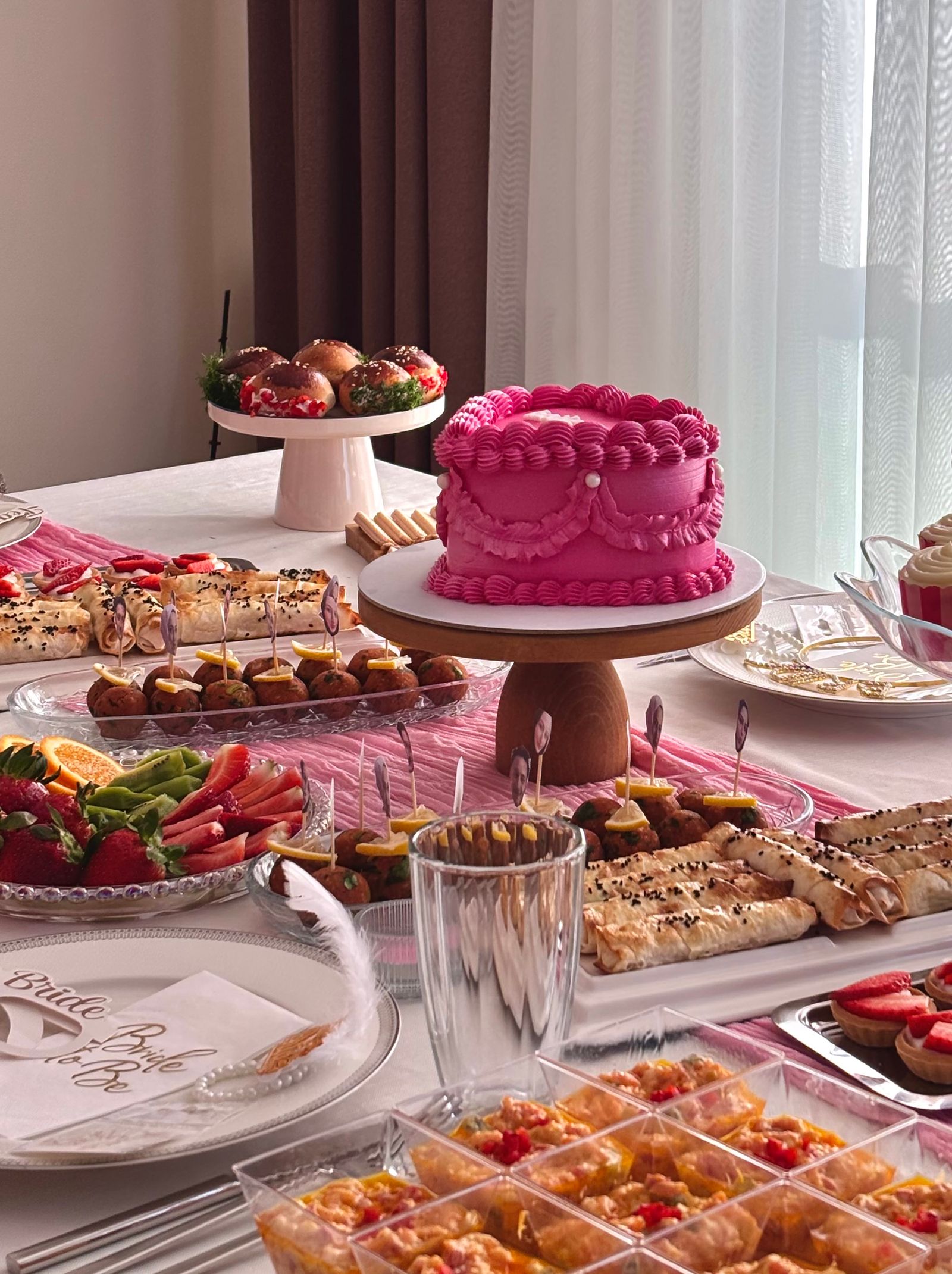 A bridal-shower table with cake, plates, and simple pink details.