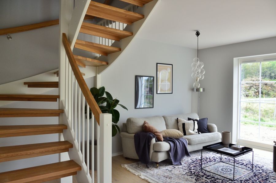 Open oak stair beside a bright living room — Alexander Zvir on Pexels