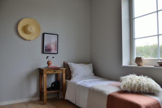Serene minimalist bedroom with rustic accents, showcasing a cozy bed, side table, and wall decor.