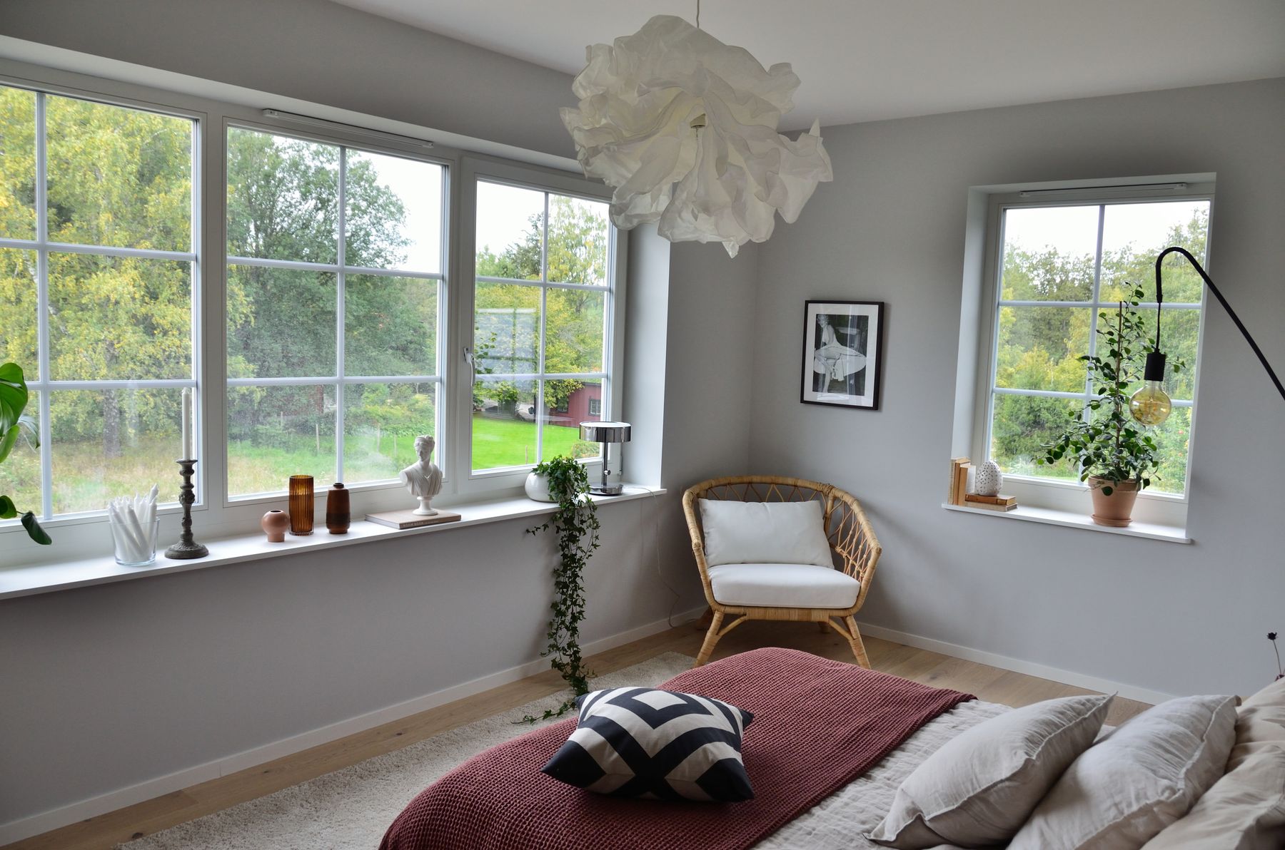 Stockholm bedroom with large windows, wood floor, greenery and soft neutral furnishings