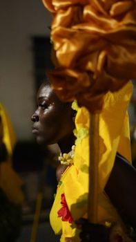 A close-up of a carnival performer in colorful traditional costume during a nighttime parade.