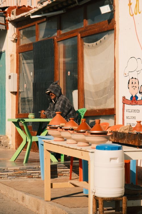 Free A person sitting near pots on an outdoor street display, bright and sunny day. Stock Photo