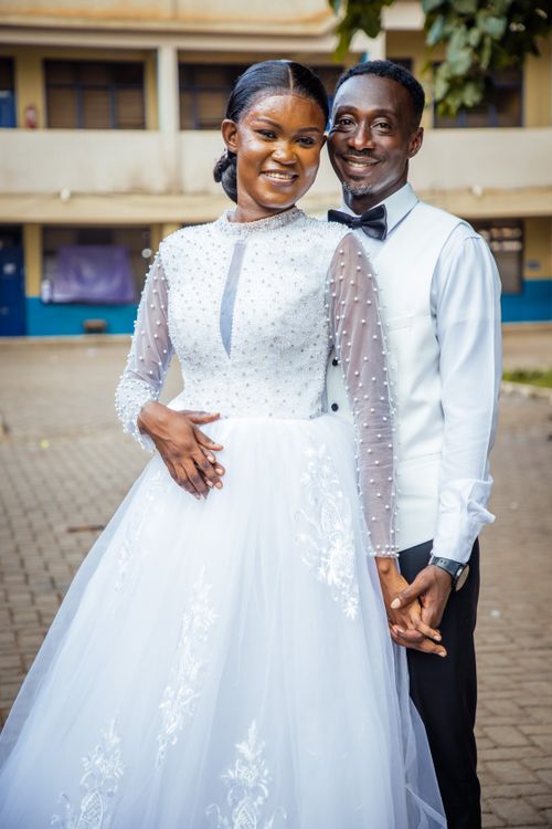 Free A joyful wedding couple posing elegantly outdoors, in stylish formal attire. Stock Photo
