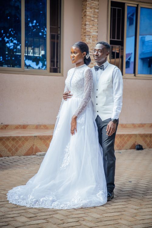 Free A couple posing in elegant wedding attire outside, captured in a romantic setting. Stock Photo