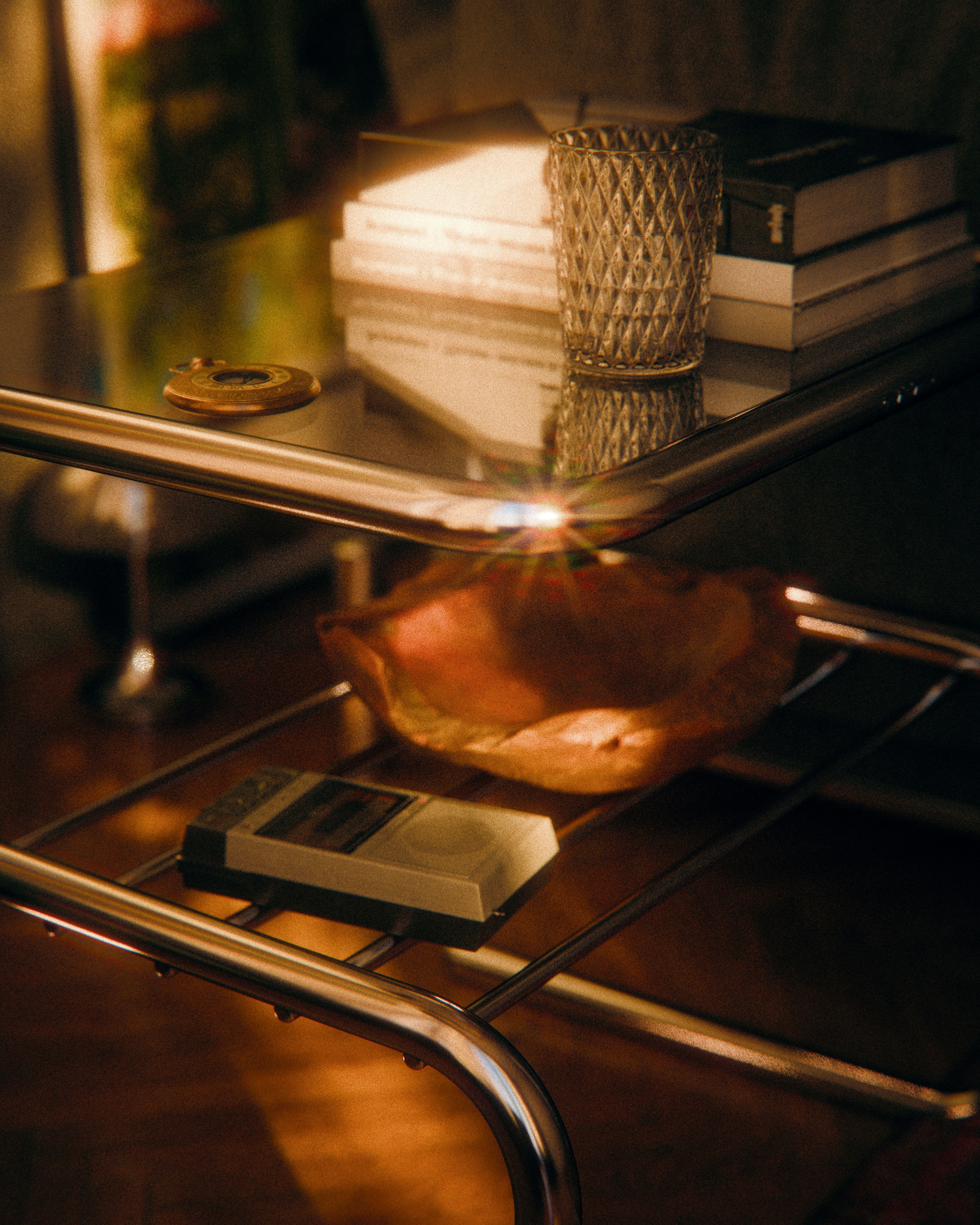 A sunlight-illuminated vintage living room setup featuring a glass table and retro items.