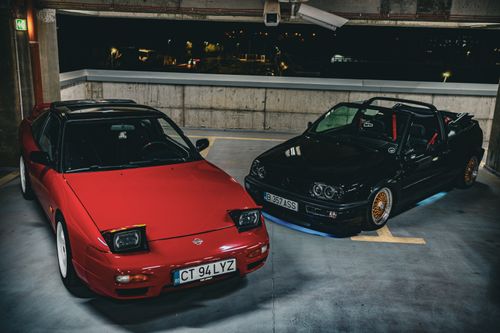 Free Two classic sports cars in a dimly lit parking garage at night, creating a dramatic urban scene. Stock Photo