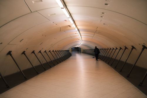 Free Long, empty underground pedestrian tunnel with soft lighting, creating a serene atmosphere. Stock Photo