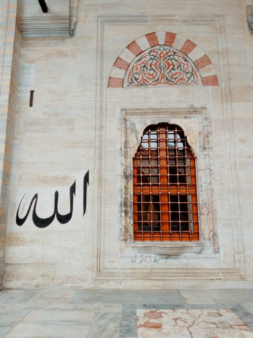 Free A historical building facade featuring a decorative window and Islamic calligraphy. Stock Photo