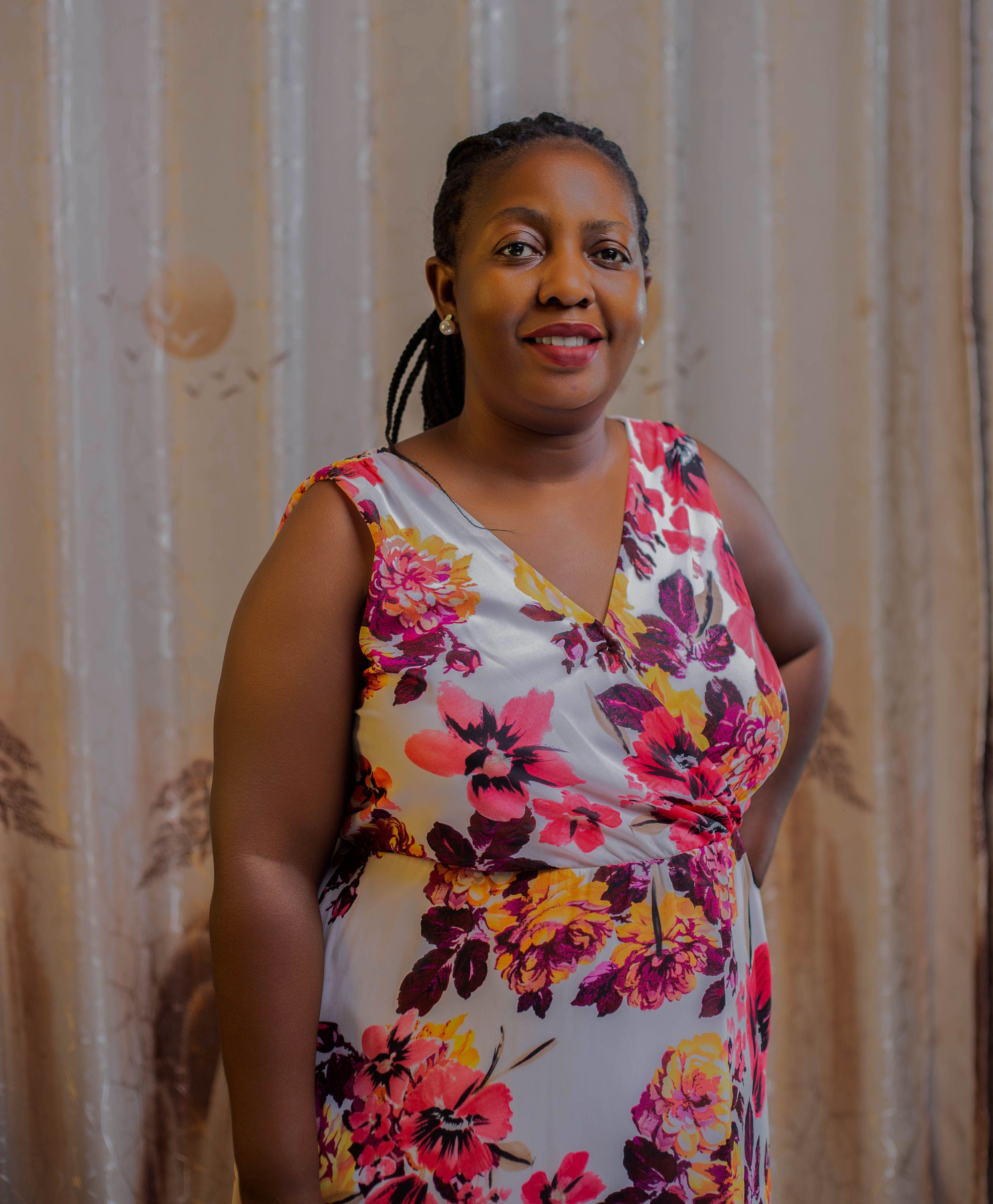 Portrait of a smiling woman in a vibrant floral dress indoors.