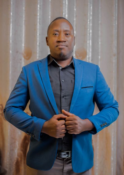 Free Portrait of a confident man in a blue suit standing against a neutral background indoors. Stock Photo