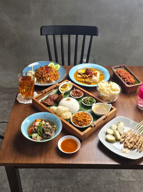 Free A vibrant display of Indonesian traditional foods on a wooden table indoors. Stock Photo