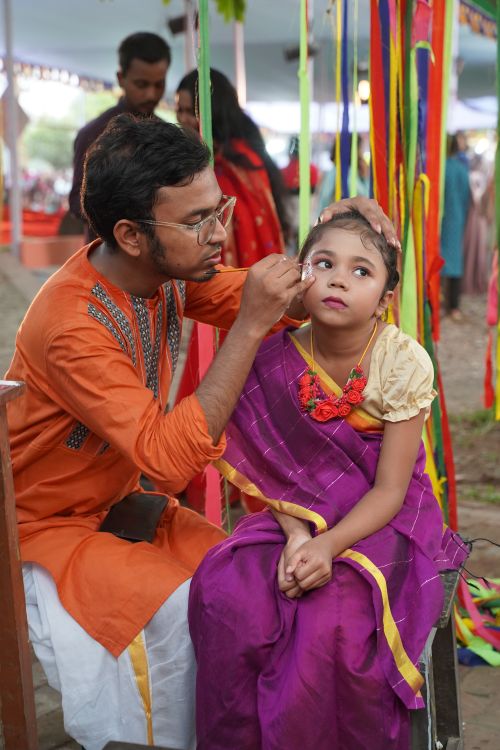 Free A young girl in traditional dress gets face paint at a cultural event outdoors. Stock Photo