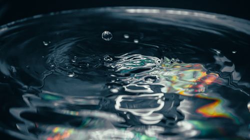 Free Close-up of a water droplet causing ripples with colorful prism reflection, captured in detail. Stock Photo