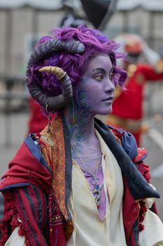 Colorful cosplay character with purple skin, intricate designs, and horned hairstyle at a cosplay event.