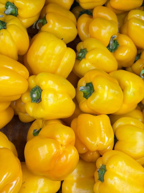 Free Close-up of fresh yellow bell peppers stacked together in a vibrant display. Stock Photo