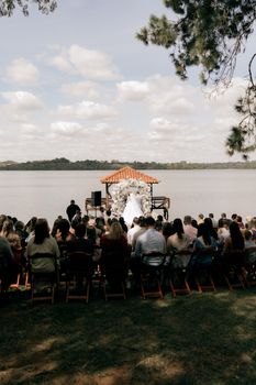 Beautiful outdoor wedding ceremony by a tranquil lakeside with guests seated.