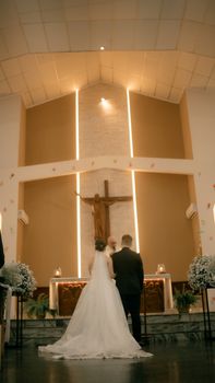 Bride and groom stand before altar during a romantic church wedding ceremony.
