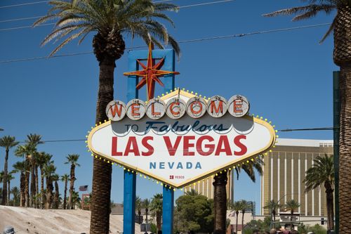 Free Famous Las Vegas sign against a clear blue sky with palm trees symbolizing vibrant city life. Stock Photo