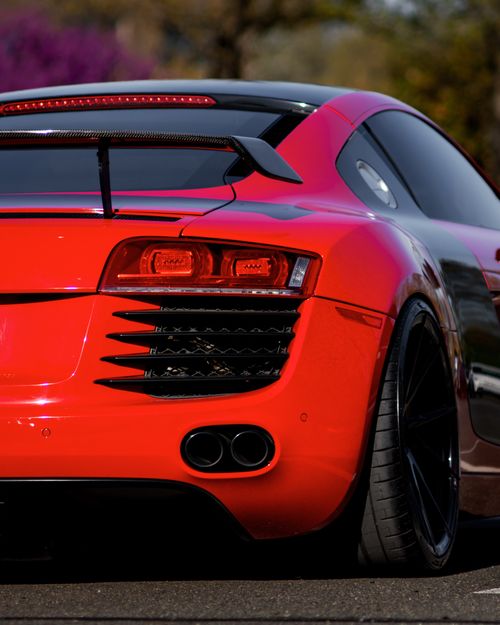 Free Rear view of a sleek red sports car parked on a sunny day, showcasing luxury and speed. Stock Photo
