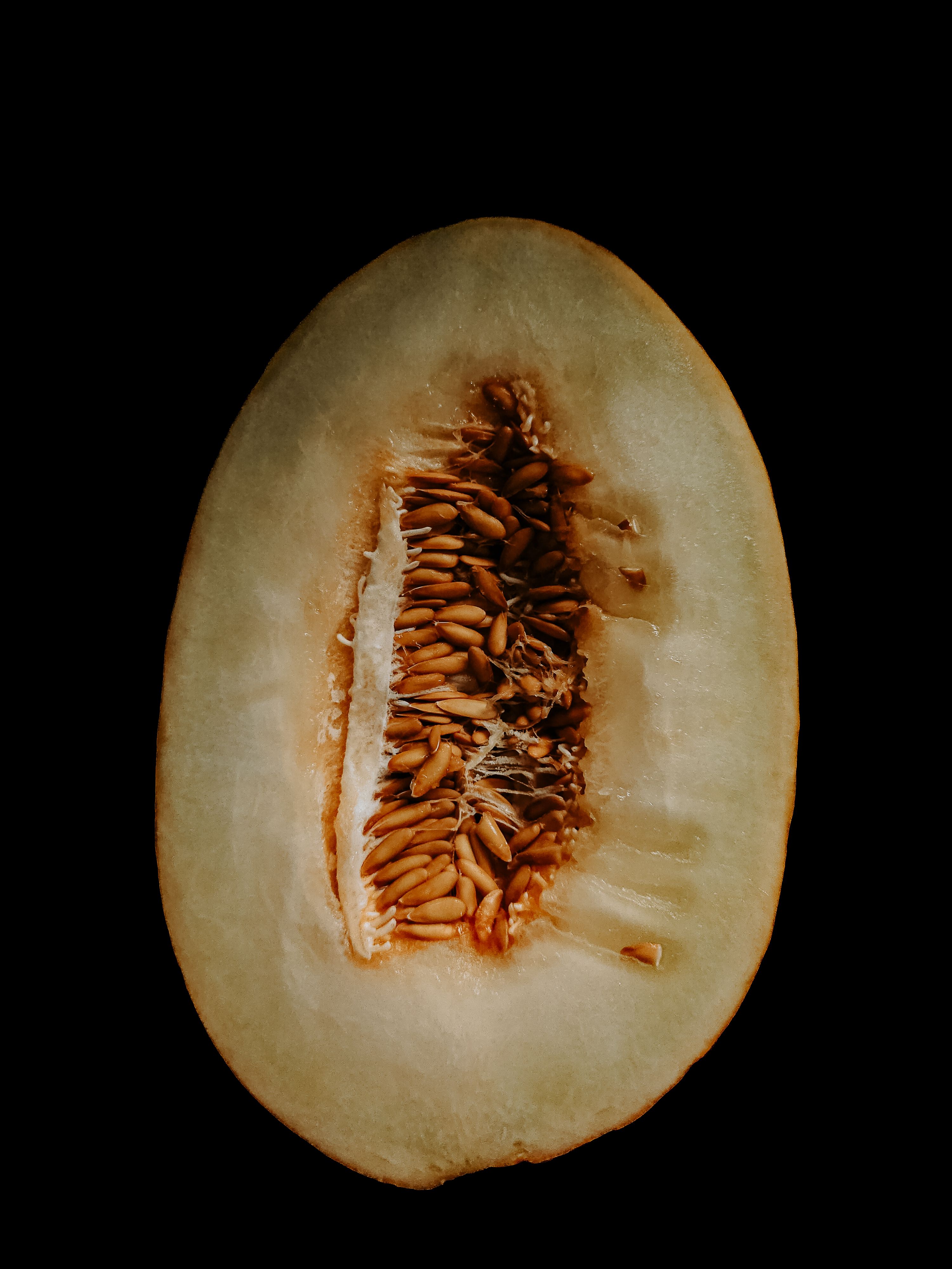 A detailed view of a halved melon showing seeds and texture against a black backdrop.