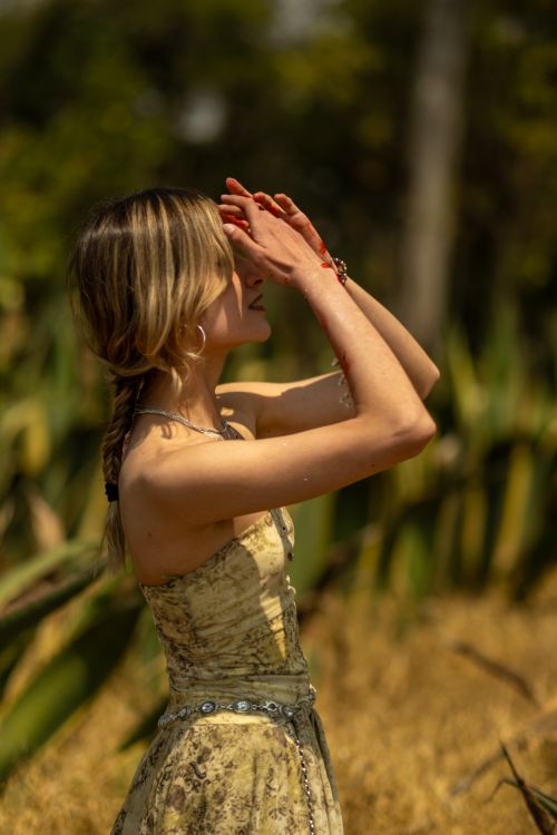 Free A woman with creative makeup stands in a sunlit field, basking in the warm daylight. Stock Photo