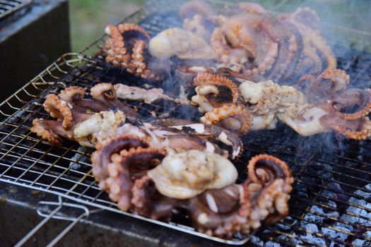 Fresh octopus sizzling on an outdoor grill, showcasing traditional seafood barbecue techniques.