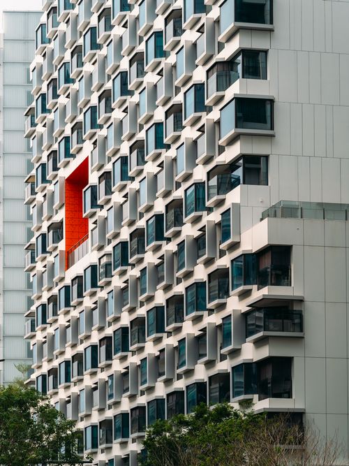 Free A modern building facade featuring a unique pattern of windows and a standout red section. Stock Photo