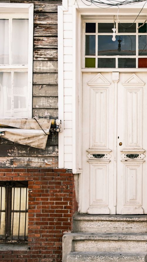 Free A vintage doorway with rustic wood and brick details, featuring a classic white door and colorful glass panels. Stock Photo