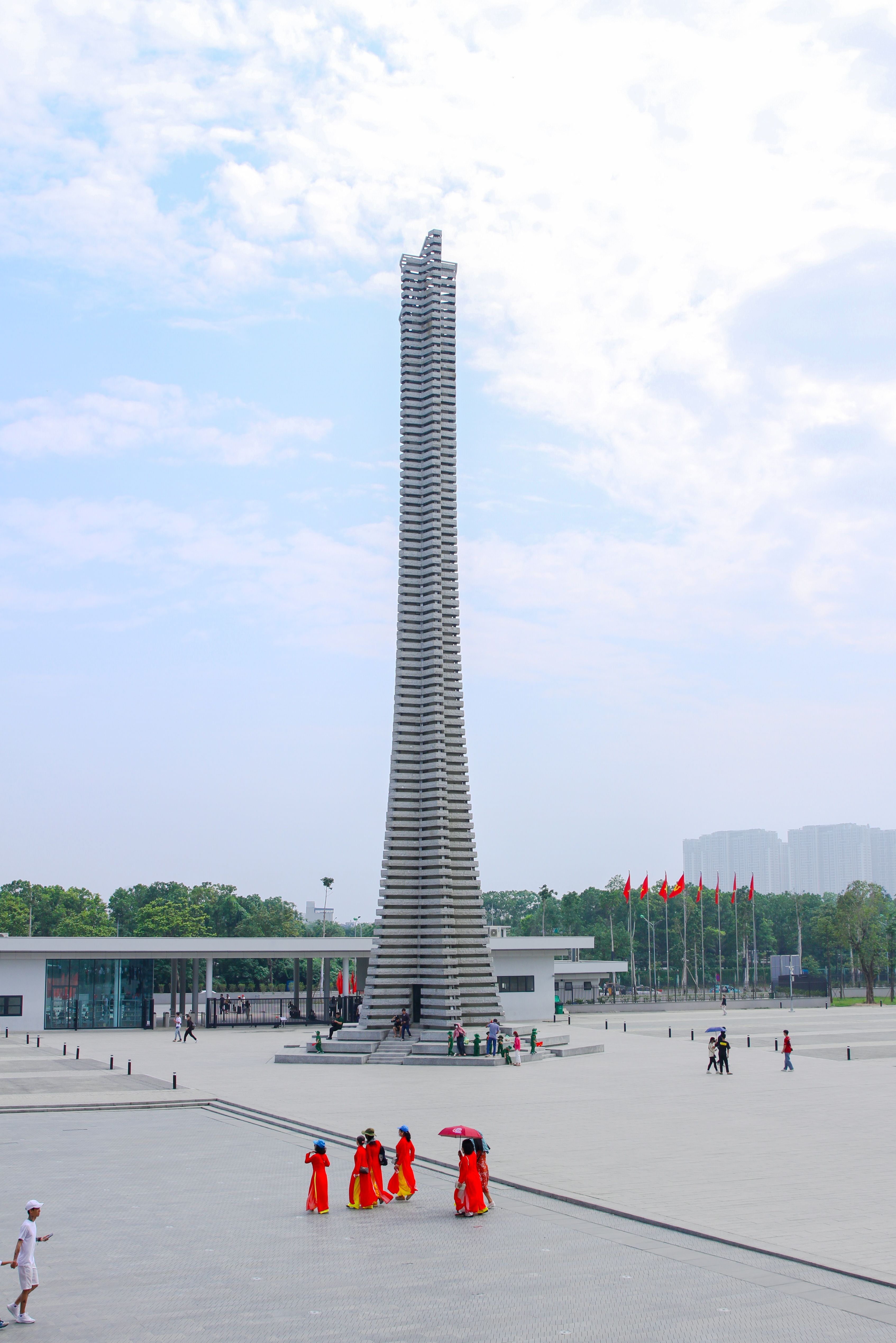 The Victory Tower stands prominently in the Vietnam Military History Museum with people around, under a bright sky.