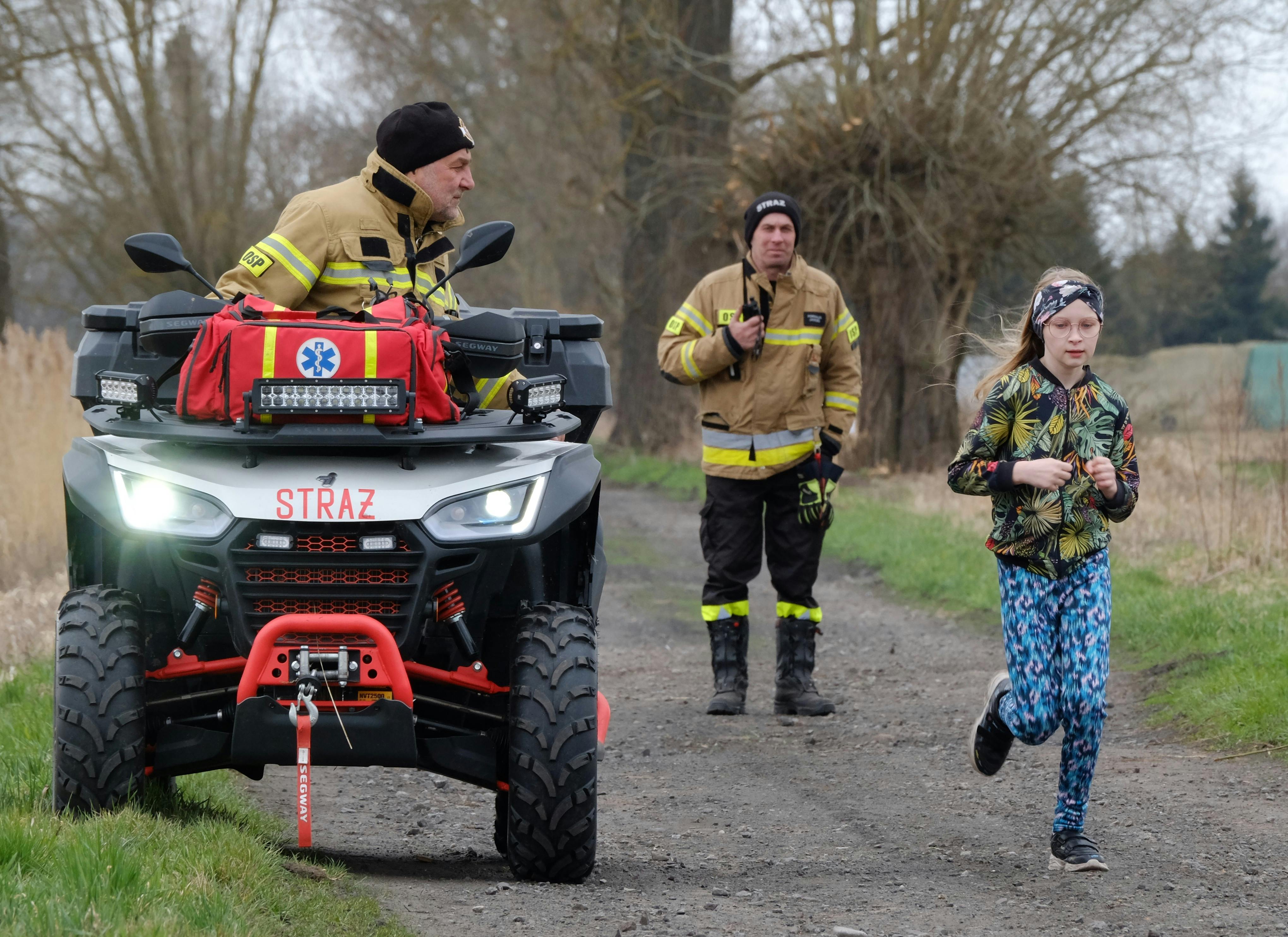 Emergency personnel assist a young girl during an outdoor event with a rescue ATV.