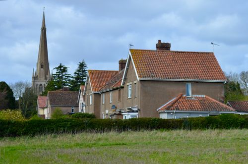 Free Scenic view of English village houses with a historic church spire in the background under a cloudy sky. Stock Photo