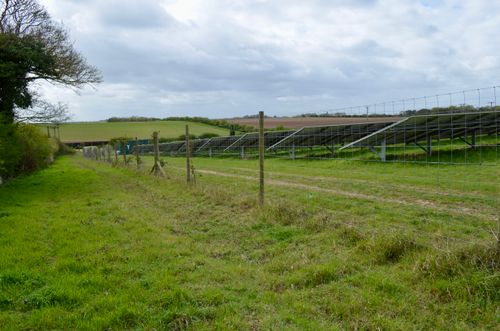 Free Solar panels installed in a rural field landscape under a cloudy sky. Stock Photo
