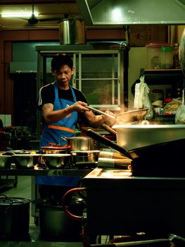 A focused chef cooking in an authentic Malaysian street kitchen in Bintulu, Sarawak.