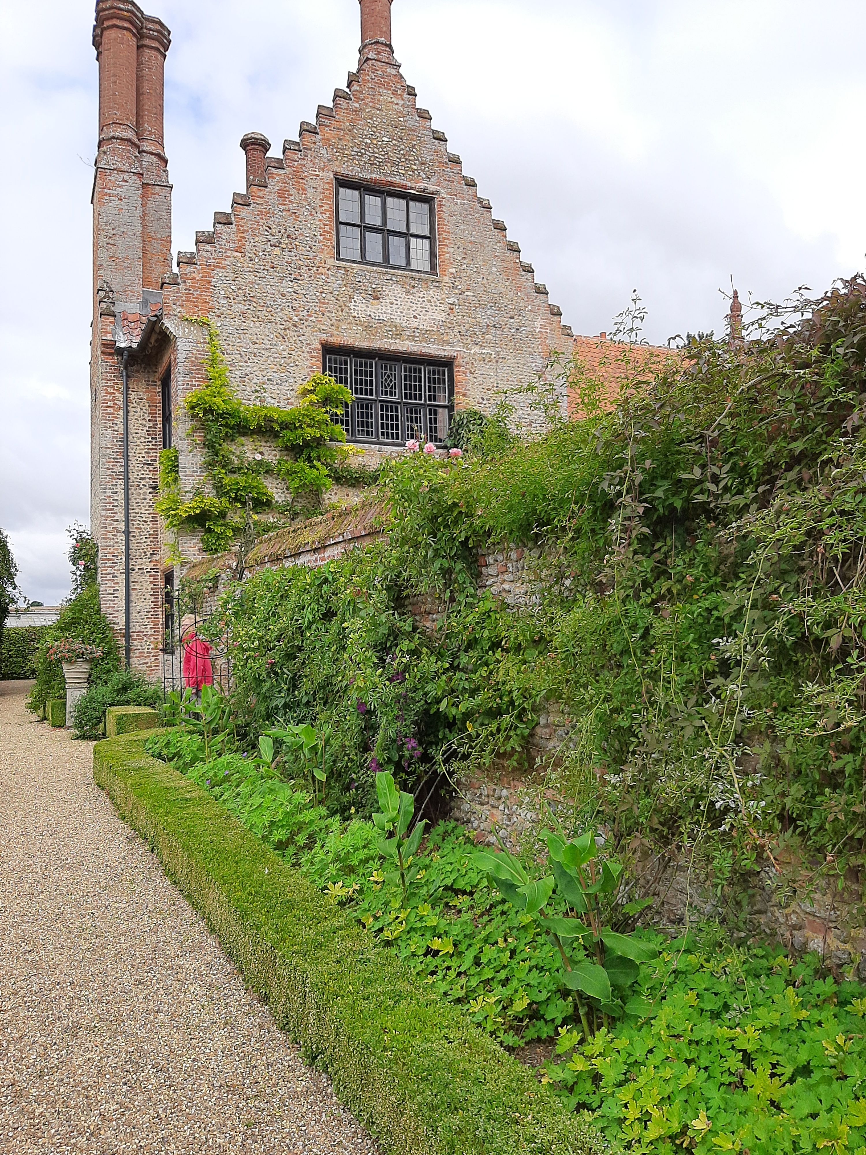A historic red-brick English manor house with garden