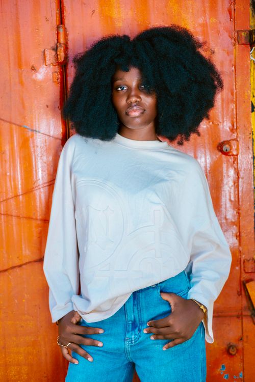 Free A stylish woman poses against a vibrant orange metal background. Stock Photo