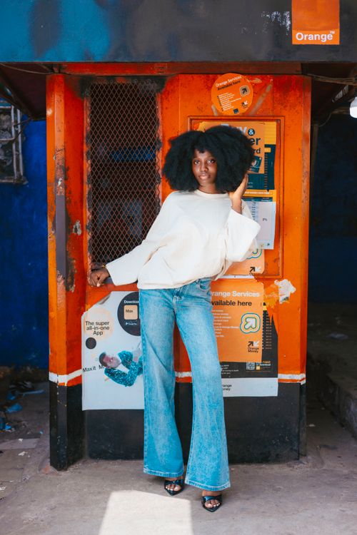 Free Stylish woman leans on vibrant kiosk in Monrovia, showcasing urban fashion and culture. Stock Photo