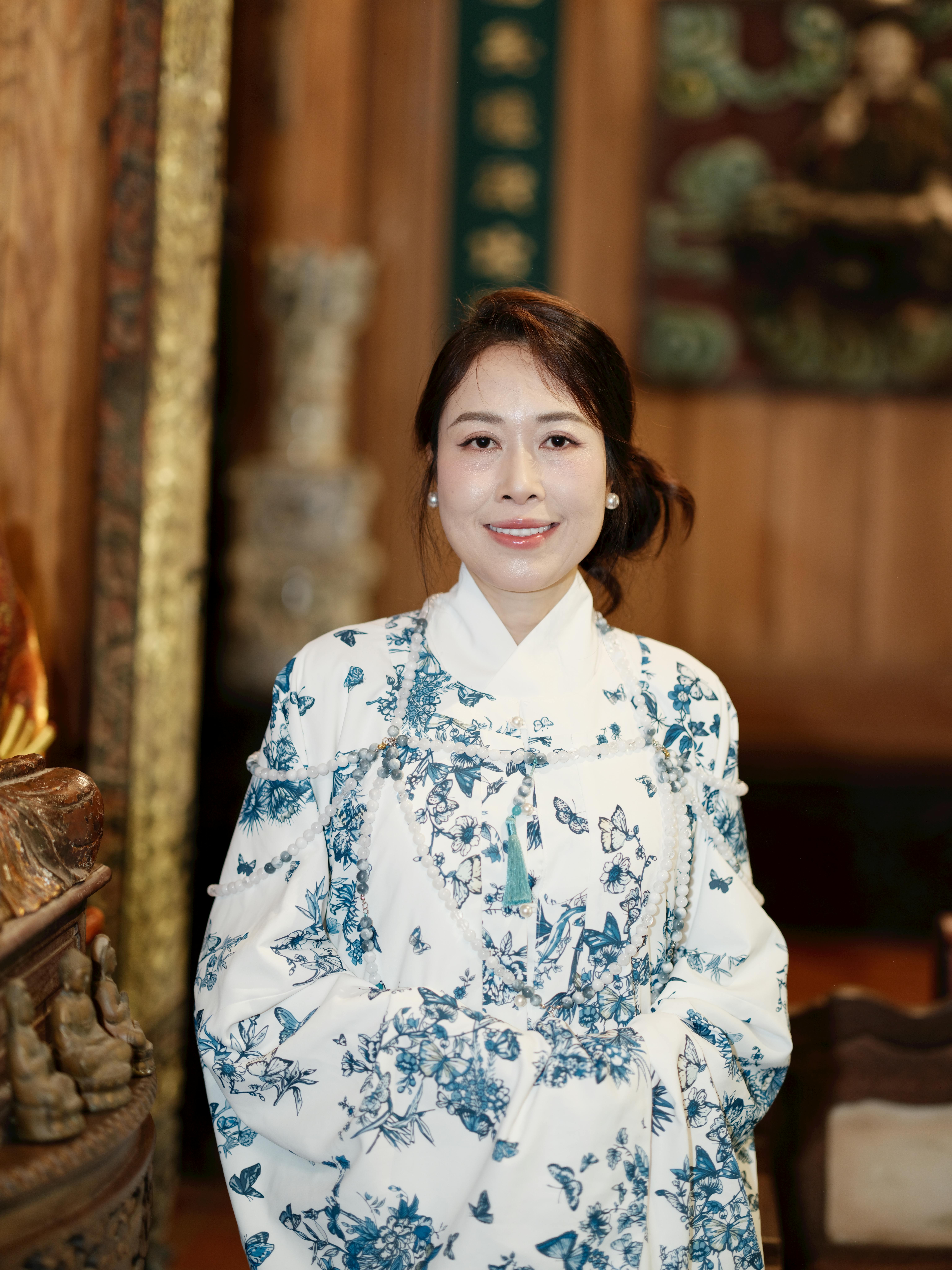 Portrait of a woman in a traditional dress, indoors with ornate wooden decor.
