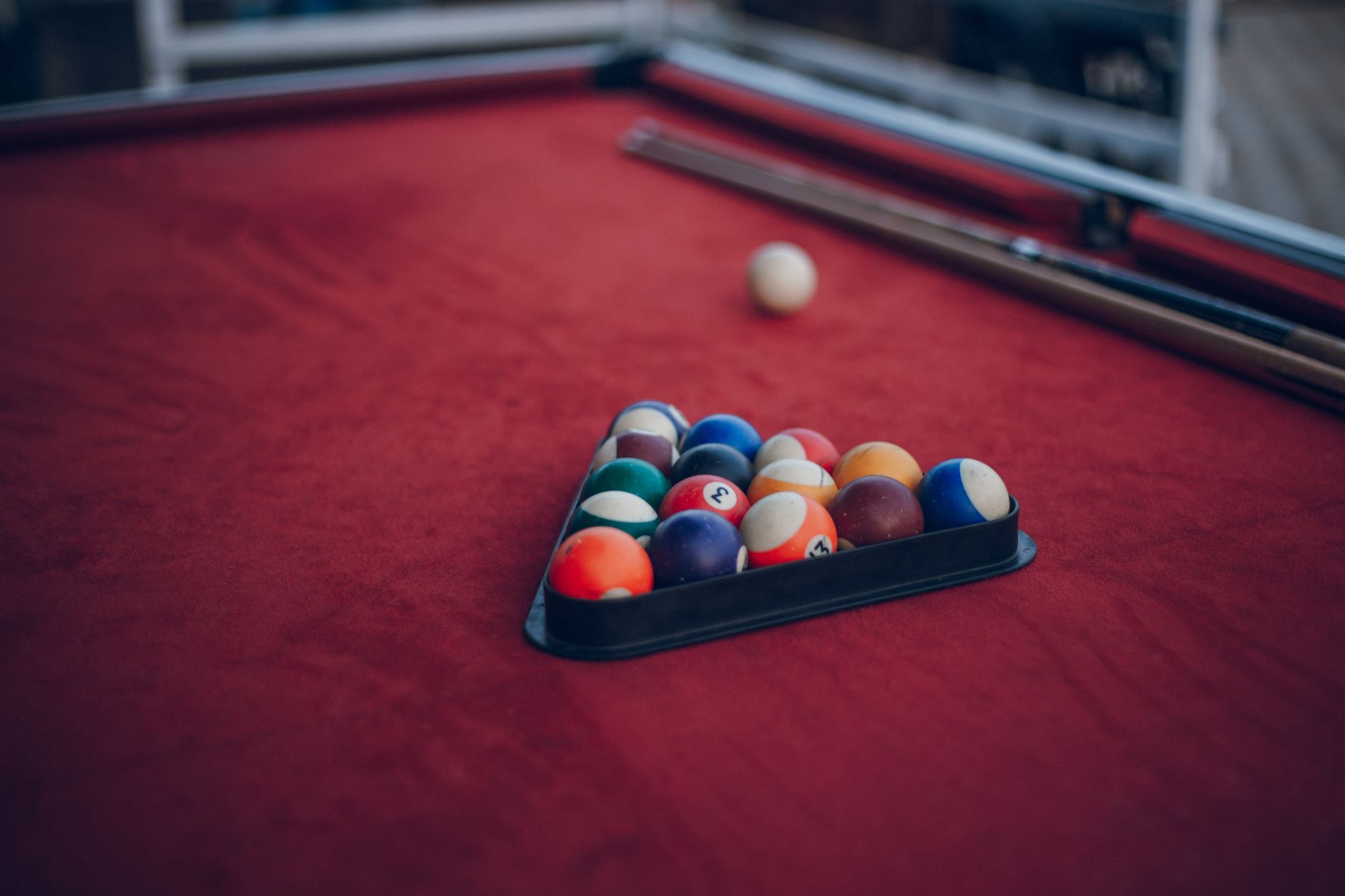 Vibrant pool balls neatly arranged on a striking red billiard table.