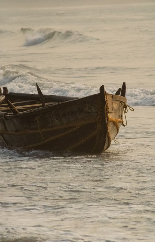 Free Close-up of a wooden boat on the ocean waves at sunrise, reflecting serenity. Stock Photo